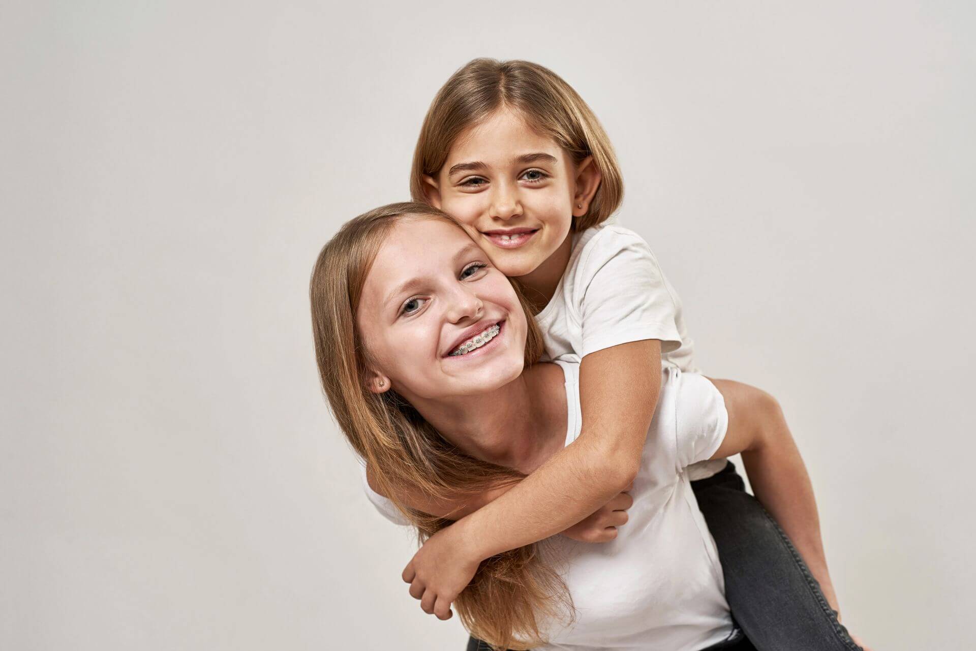 two smiling children, one wearing braces